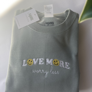 Sage green sweatshirt with Love more worry less embroidered text.
