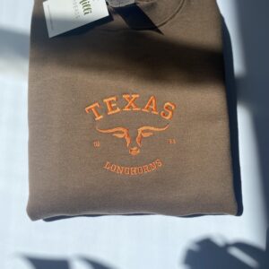 Embroidered Texas Longhorn university with burnt orange color on the brown sweatshirt.