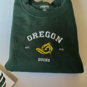 Embroidered Oregon university with a yellow mean duck head on a forest green color sweatshirt.